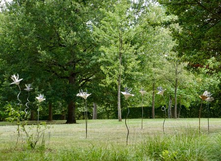 Installation au domaine de Poulaines de 10 fleurs en acier, tissus de verre, r&eacute;sines teint&eacute;es et enjoliveurs transform&eacute;s (Corolles entre 35 et 45 cm de circonf&eacute;rence, tiges de 120 &agrave; 220 cm de hauteur)